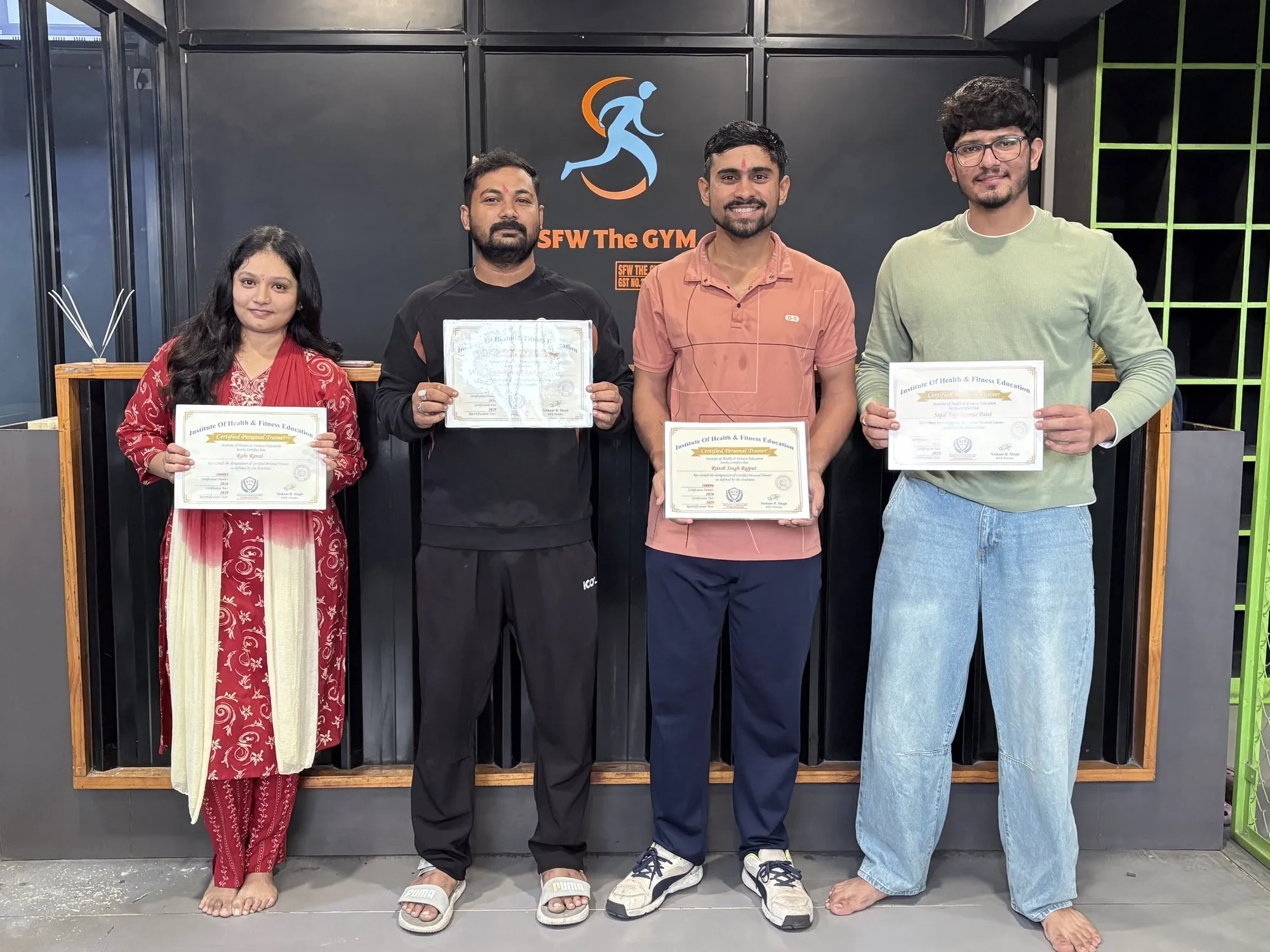 Four newly certified personal trainers holding their IHFE Certified Personal Trainer certificates