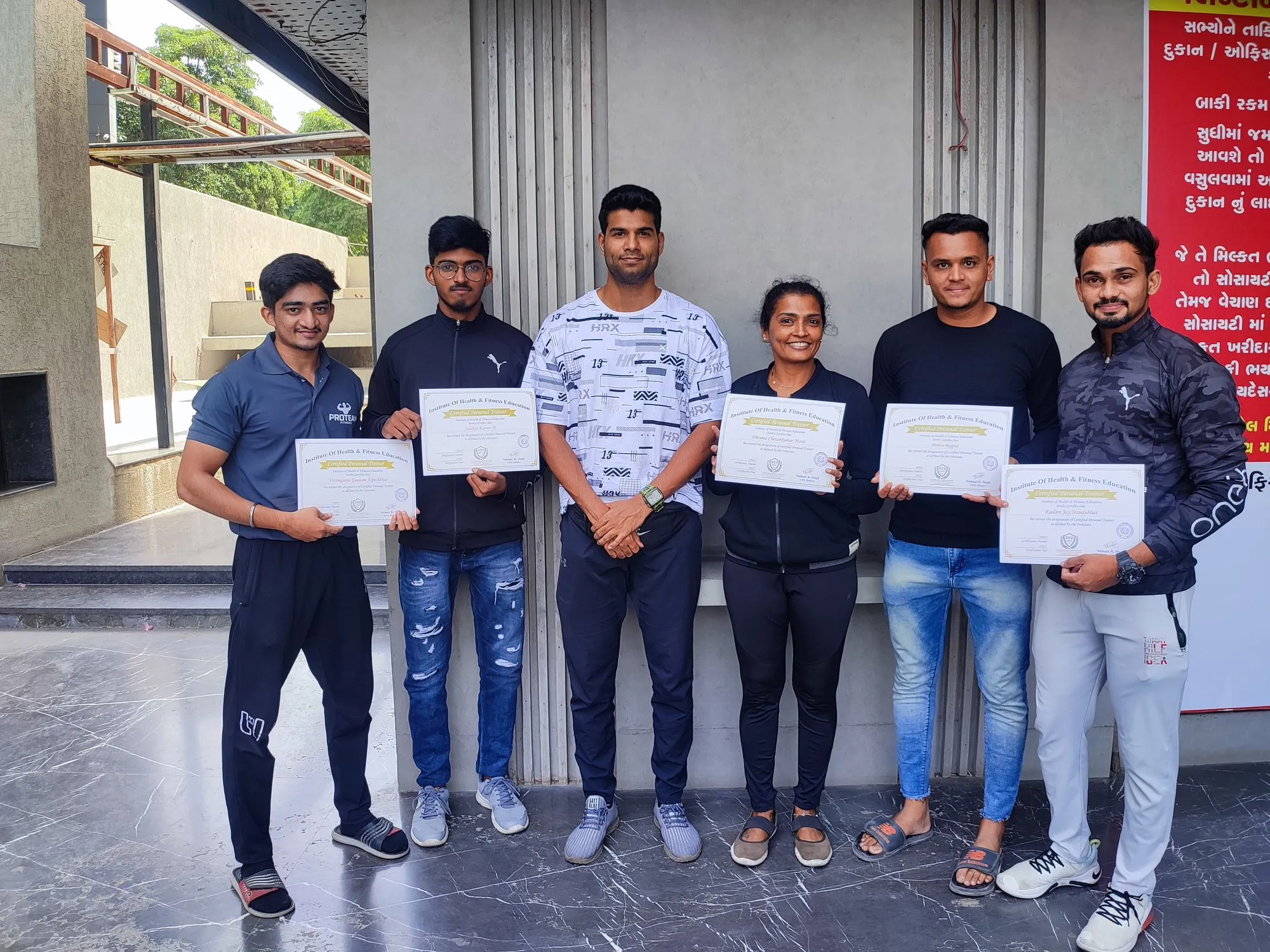 Six IHFE graduates holding Certified Personal Trainer certificates with their instructor
