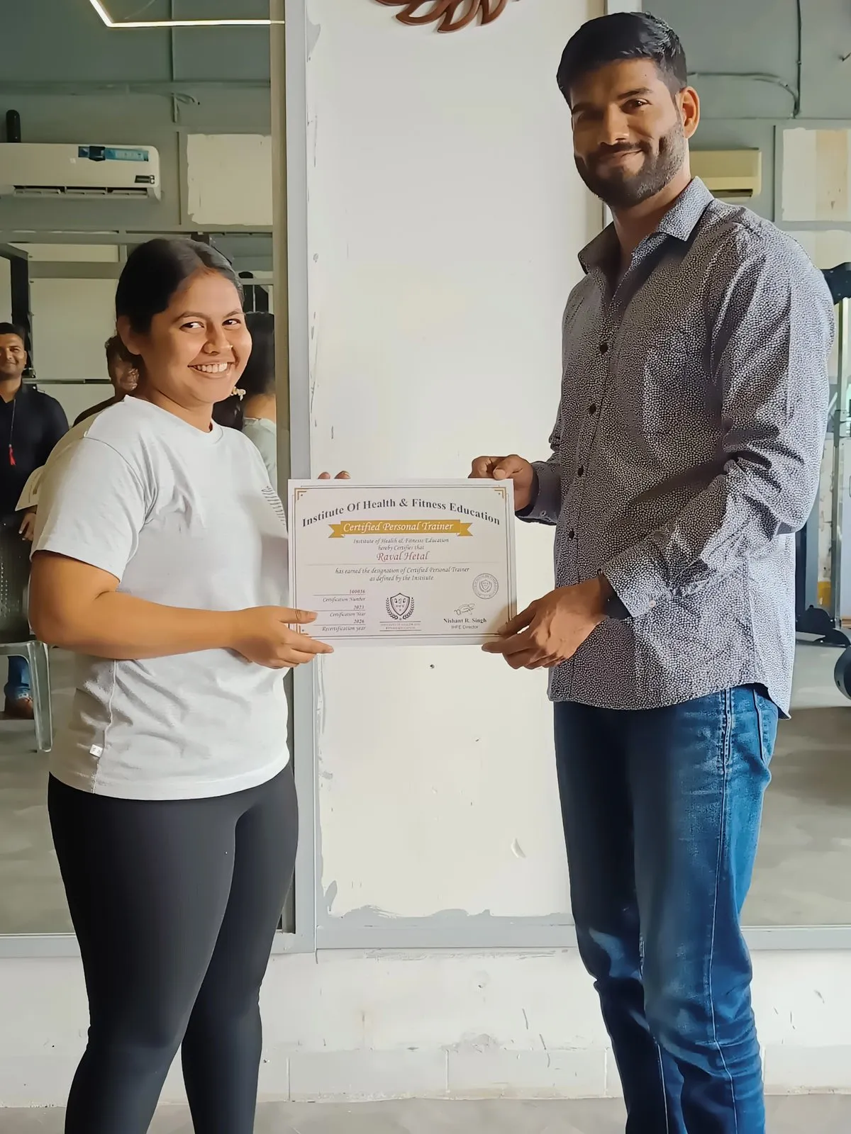 Graduate smiling as she receives her IHFE Certified Personal Trainer certificate