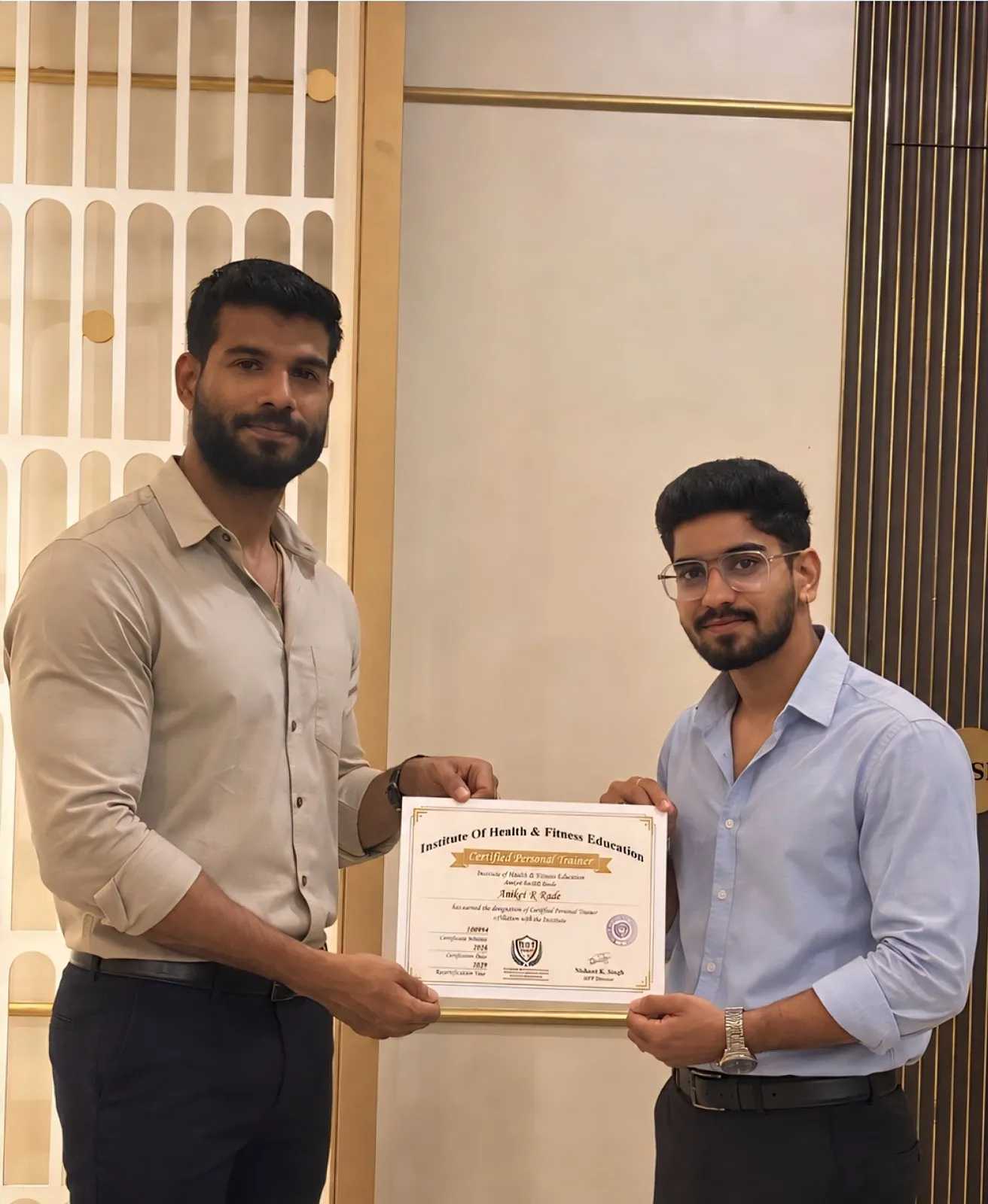 Graduate in glasses receiving an IHFE Certified Personal Trainer certificate