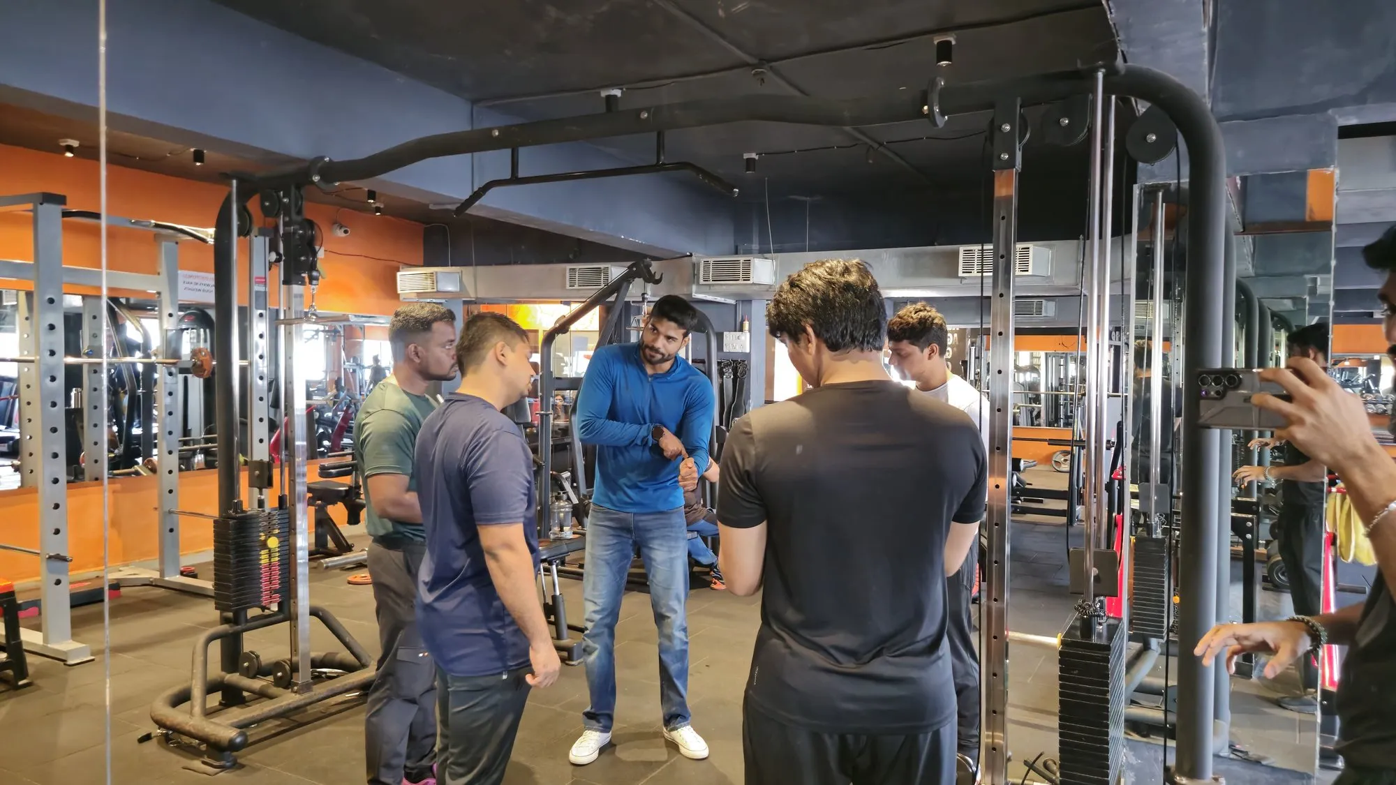 IHFE instructor demonstrating correct arm positioning to trainee personal trainers on the gym floor